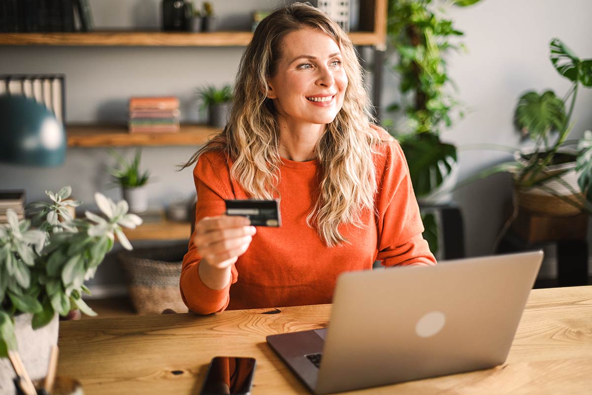 mature woman smiling holding a credit card